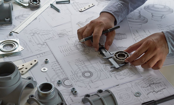 Engineer measuring components on technical blueprints